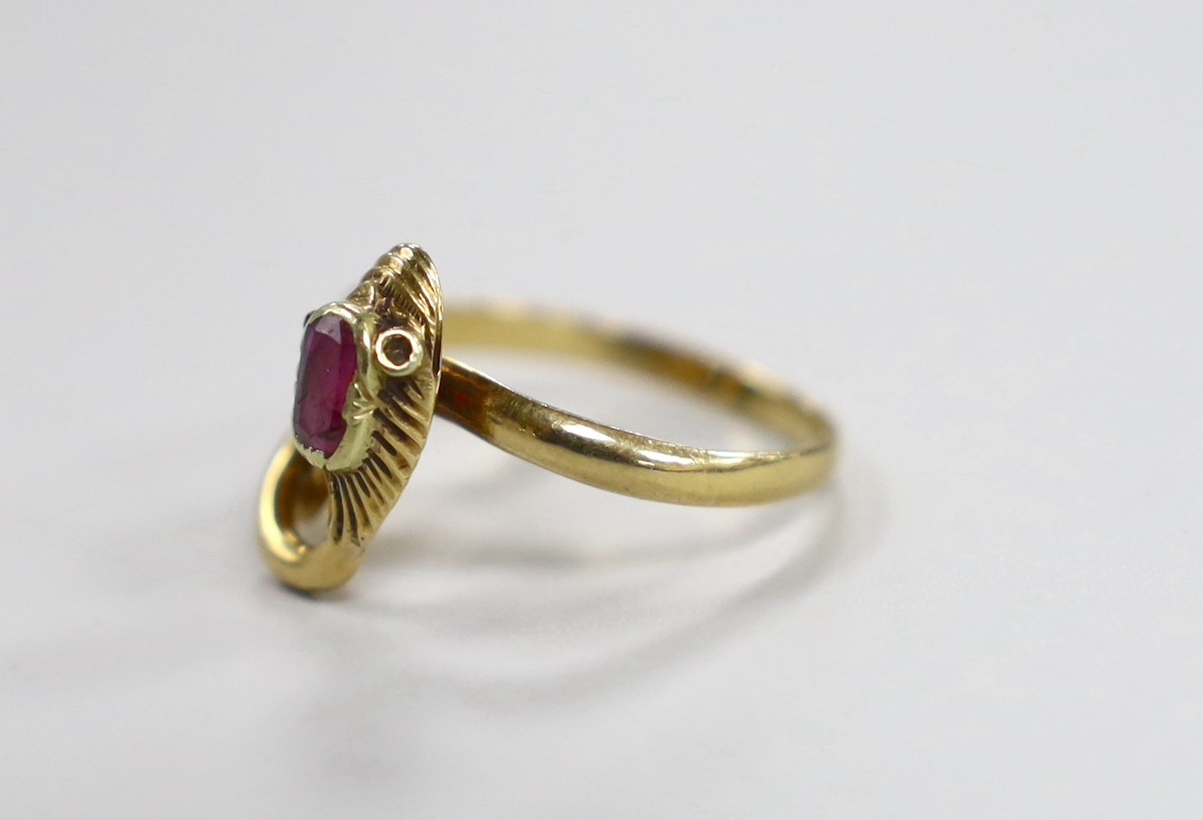 An early 20th century yellow metal and single stone garnet set entwined serpent ring, with diamond chip eyes, size O, gross weight 3.7 grams.